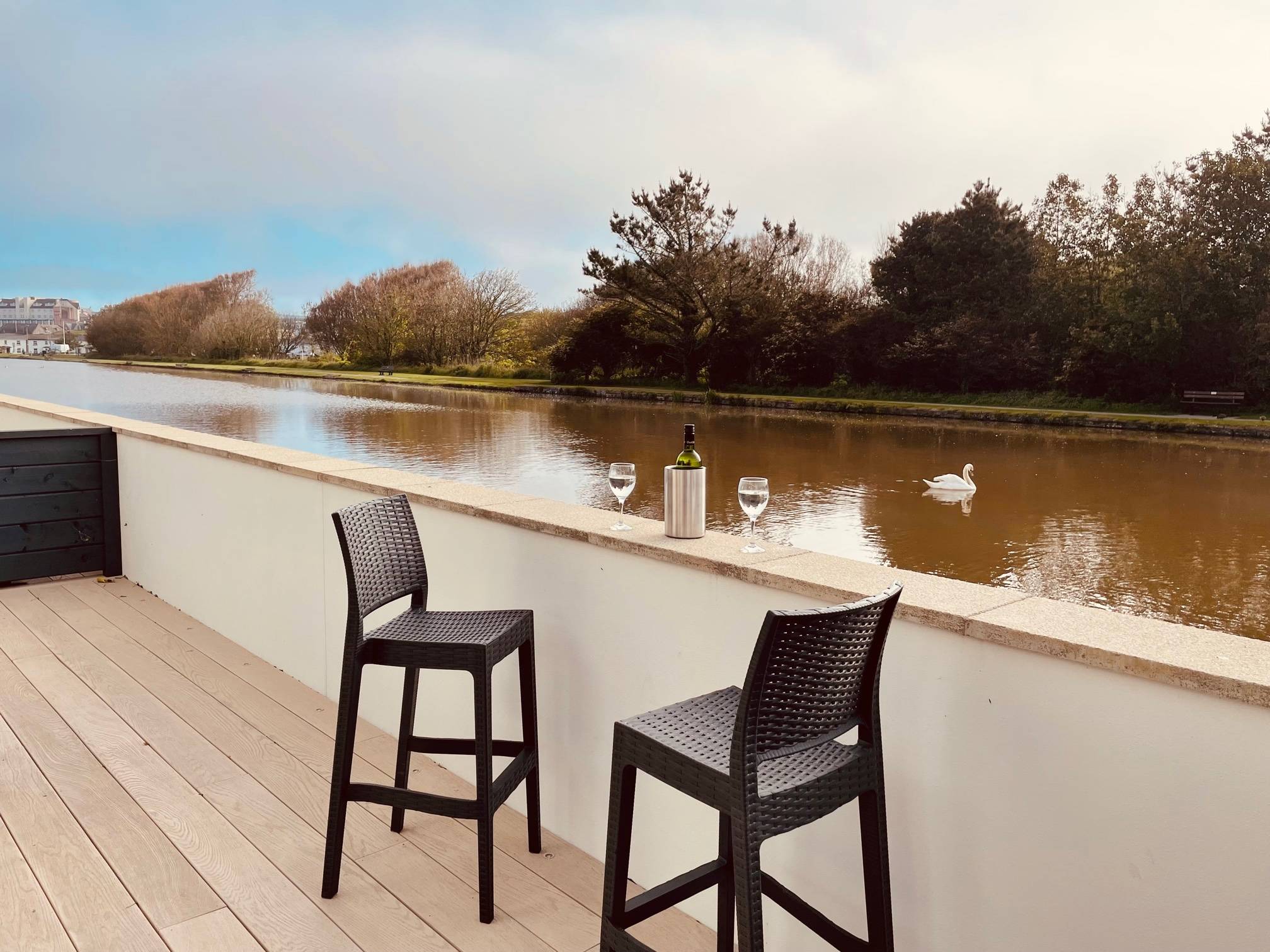 Image of 2 high chairs with drinks on wall, overlooking Bude canal